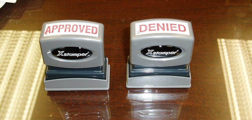 standard office stamps on desk; one reads “APPROVED”; the other, “DENIED”