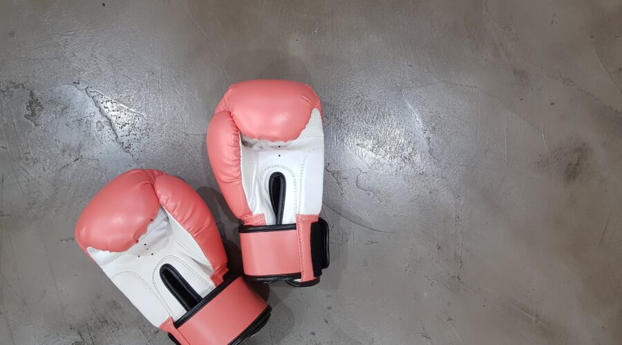 a pair of pink and white boxing gloves lie on a concrete surface