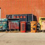 A collection of colorful, art-covered dumpsters and trash bins. They are the medium; what message to they convey?