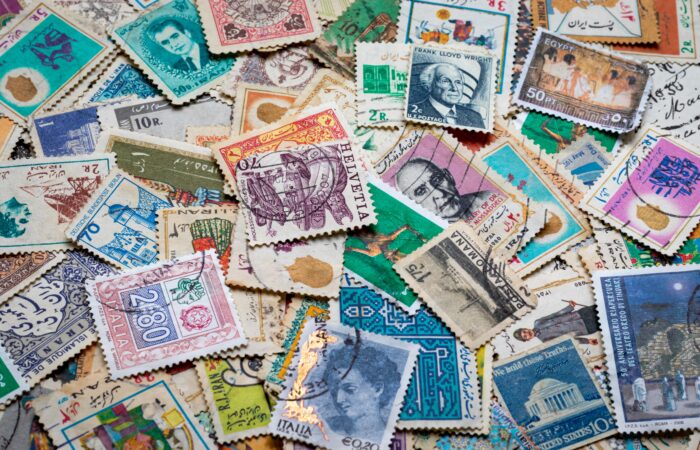 A pile of various colorful stamps, mostly canceled and weathered. What discourse communities do they represent?